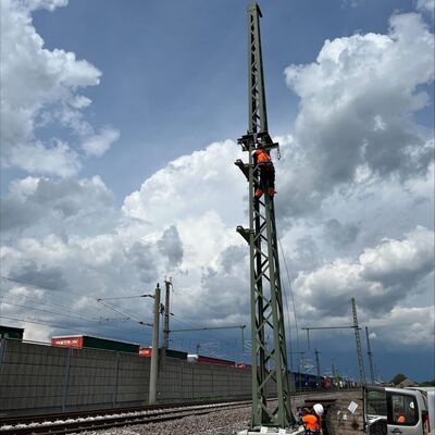 Eine Person klettert auf einen Bahnstrommast.
